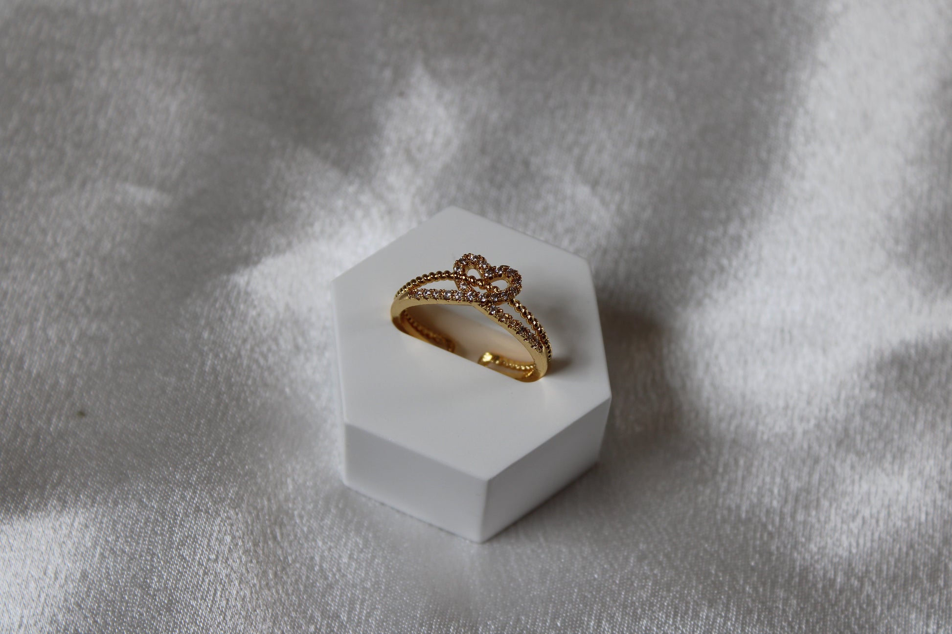 Verstellbarer goldfarbener Ring mit Herzkrone und Zirkonsteinen auf weißem Schmuckständer.